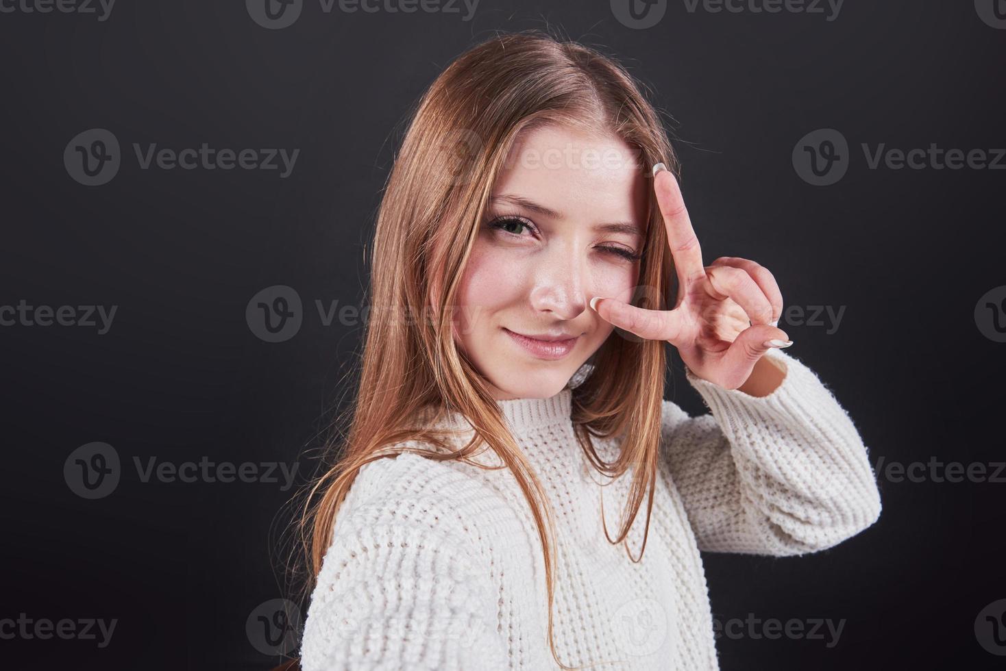 Close up portrait of beautiful young woman in white sweater and jeans, isolated on black background photo