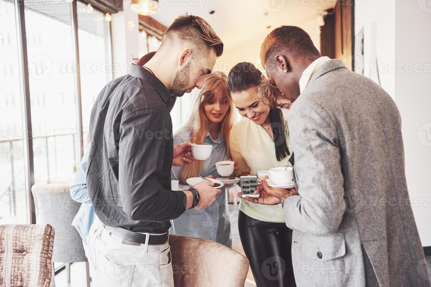 Los jóvenes empresarios exitosos están hablando y sonriendo durante la pausa para el café en la oficina foto