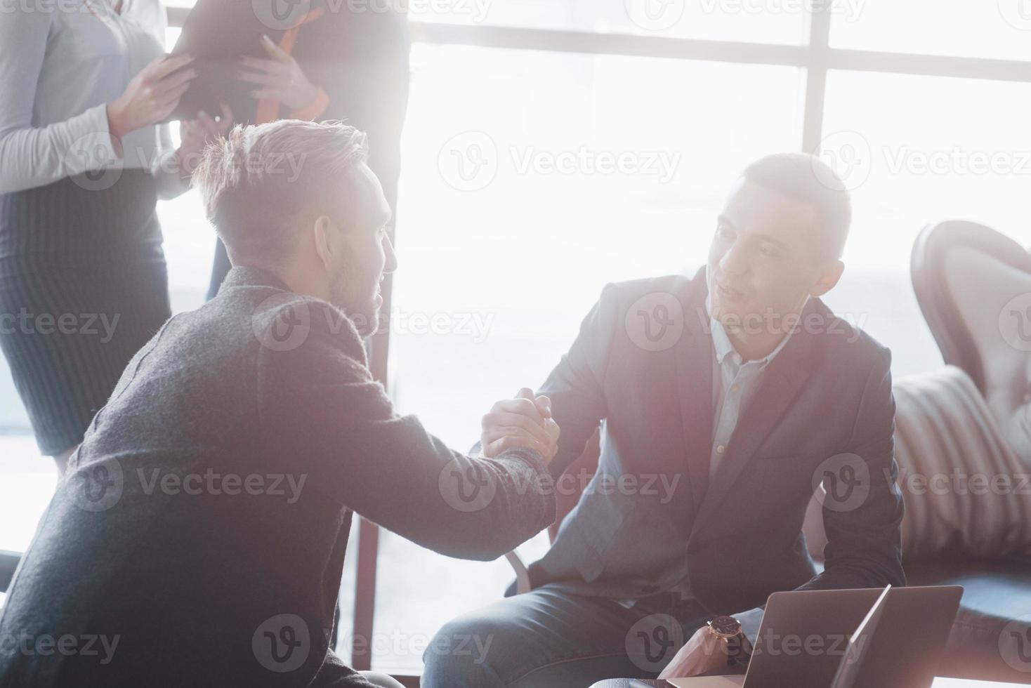 Dos hombre de negocios confiado dándose la mano durante una reunión en la oficina, el éxito, el trato, el saludo y el concepto de socio foto