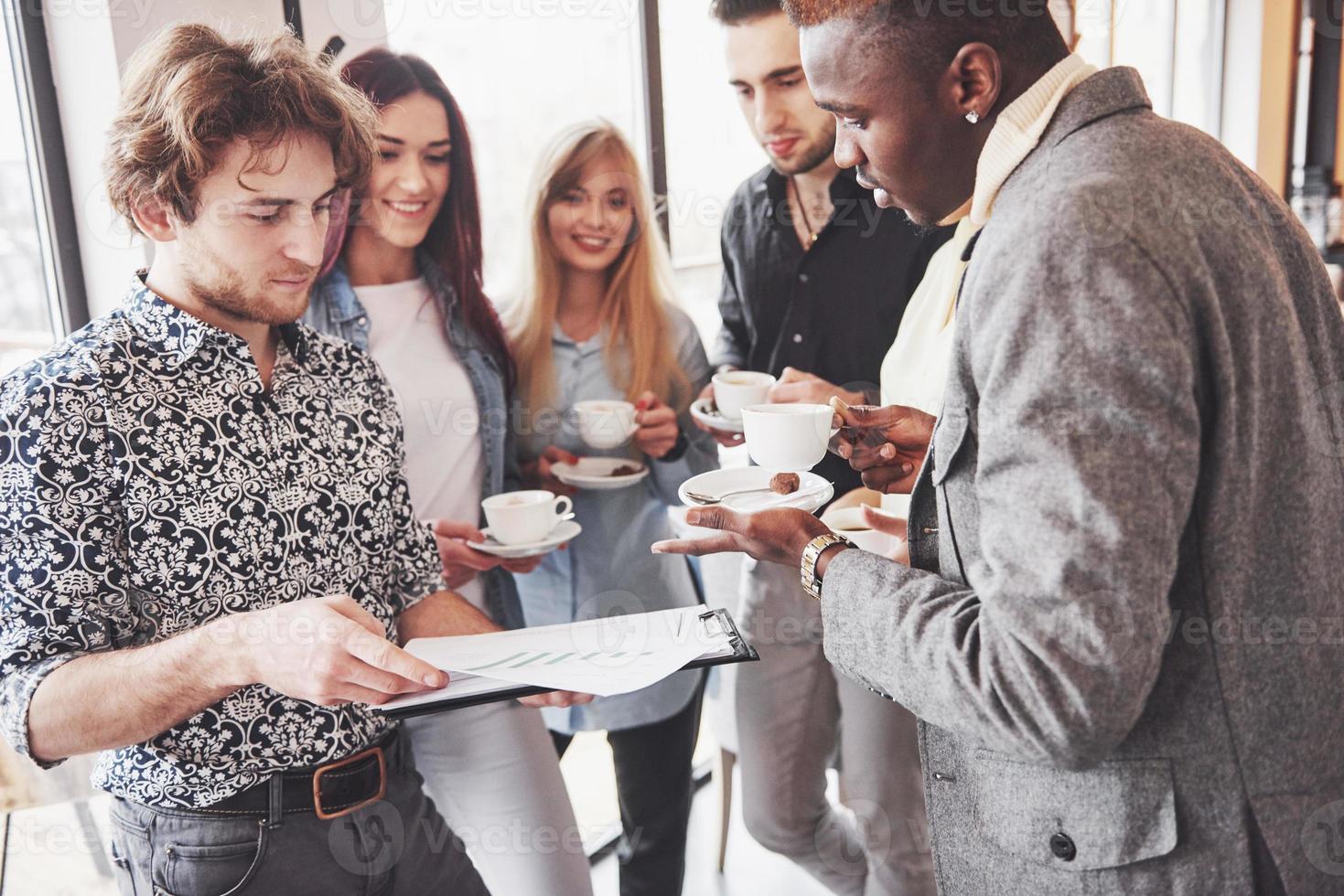 Successful young business people are talking and smiling during the coffee break in office photo