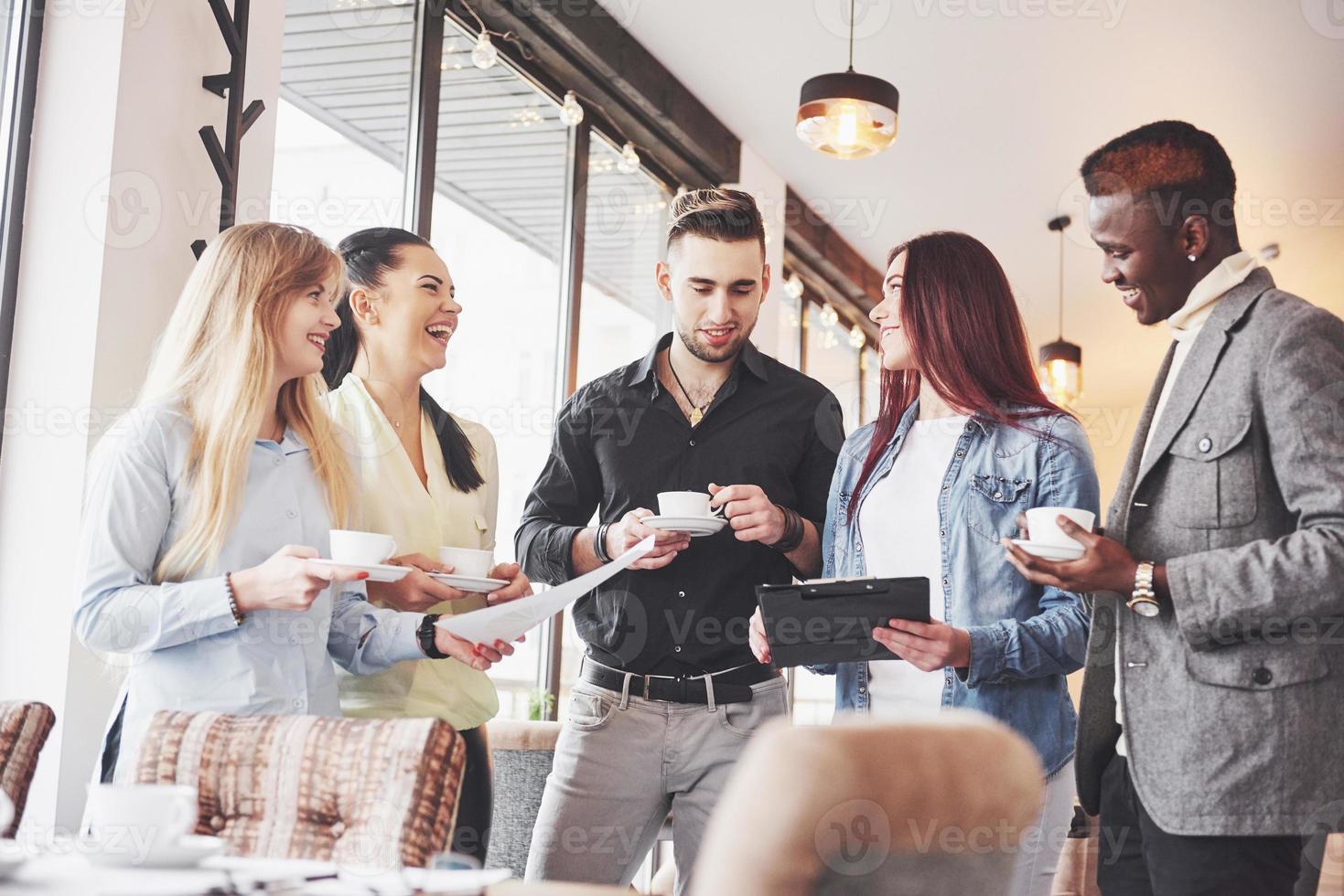 Los jóvenes empresarios exitosos están hablando y sonriendo durante la pausa para el café en la oficina foto