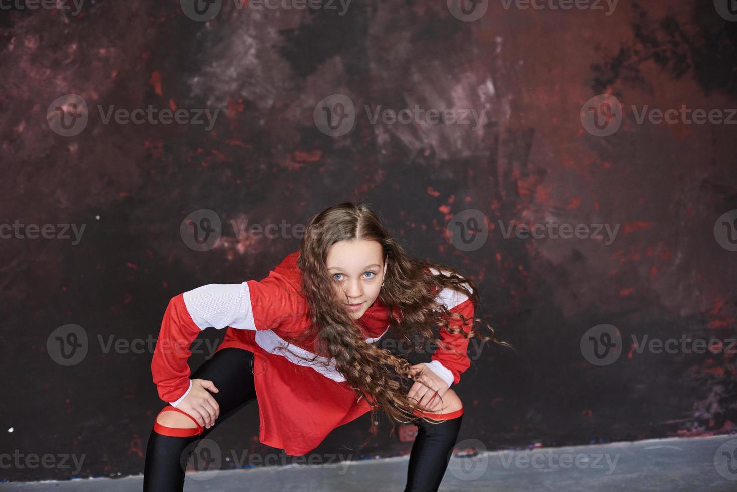 Young beautiful girl dancing in a trendy clothes on a grunge background photo