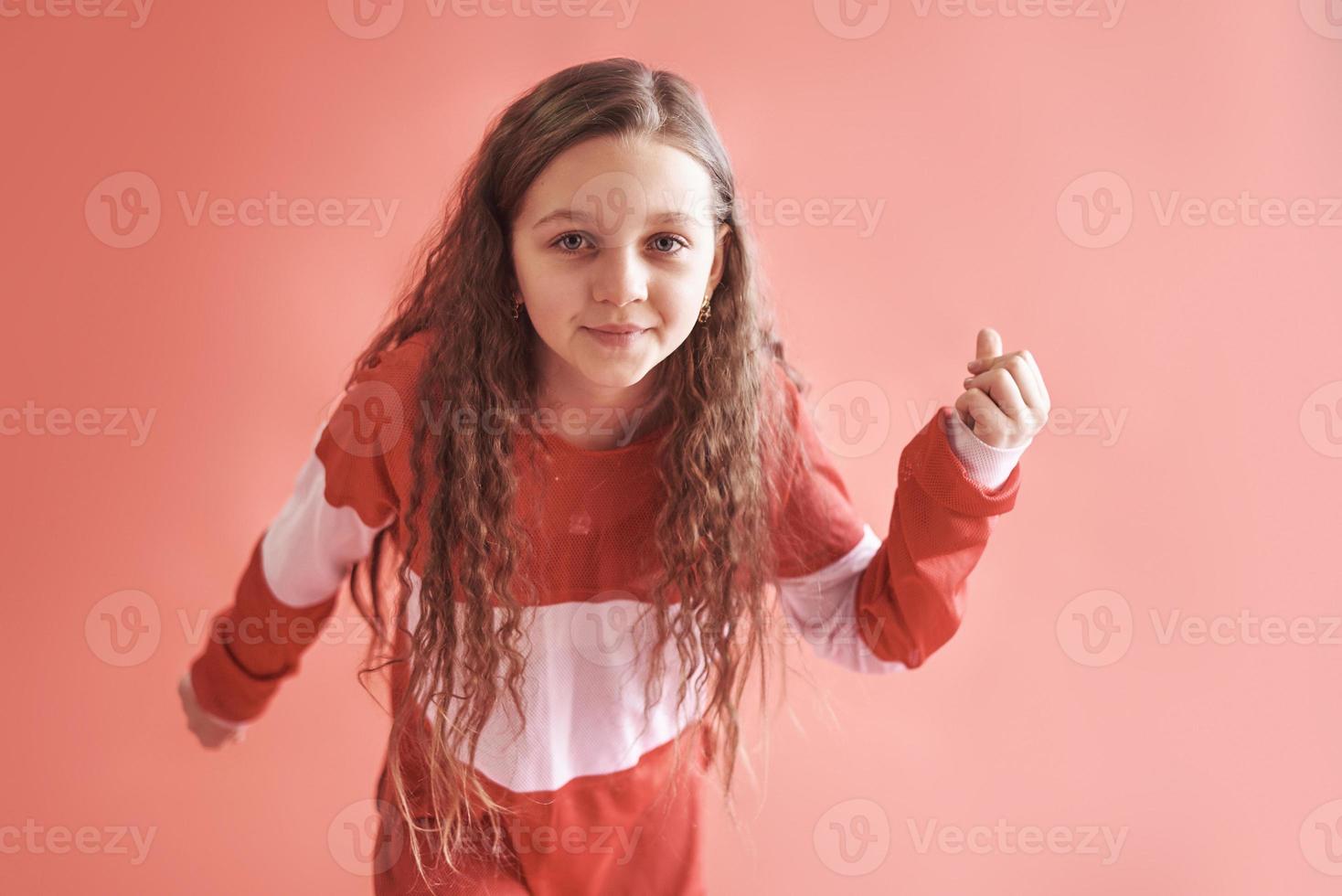 Young beautiful cute girl dancing on red background, modern slim hip-hop style teenage girl jumping photo