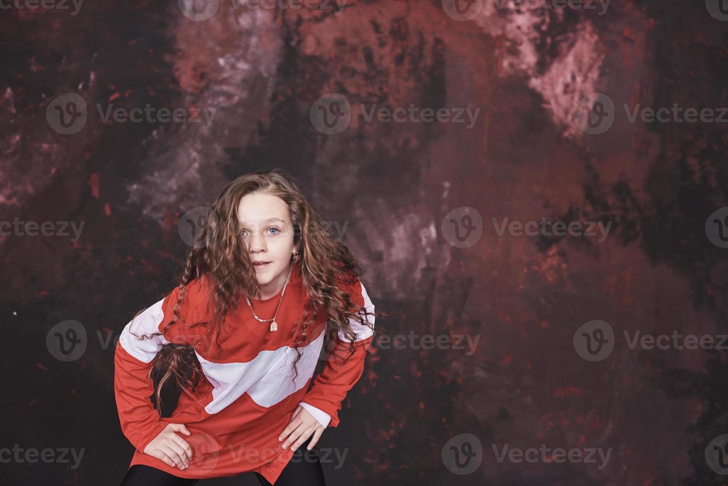 Young beautiful girl dancing in a trendy clothes on a grunge background photo