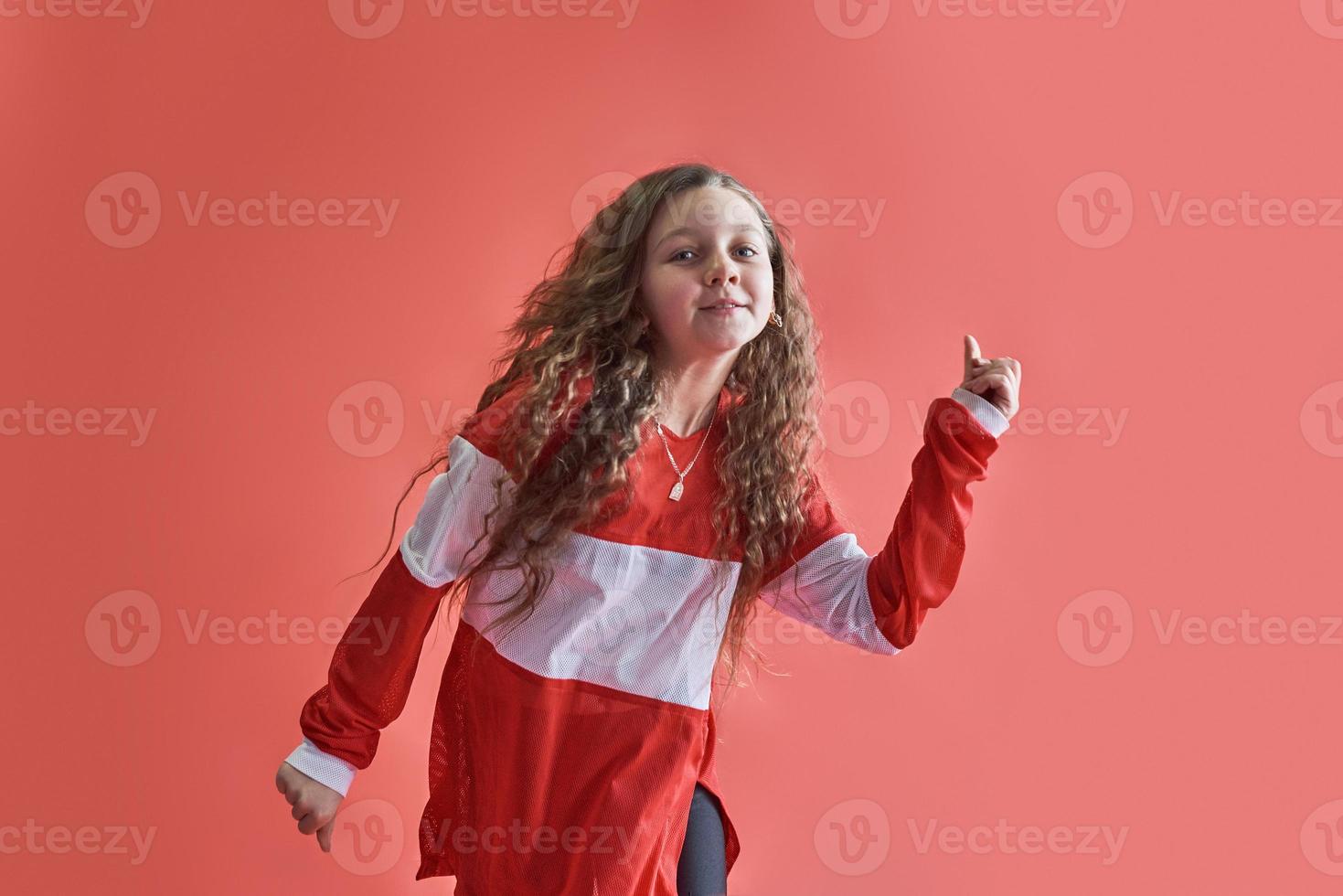 Joven mujer urbana bailando sobre fondo rojo, moderno estilo hip-hop delgado adolescente foto