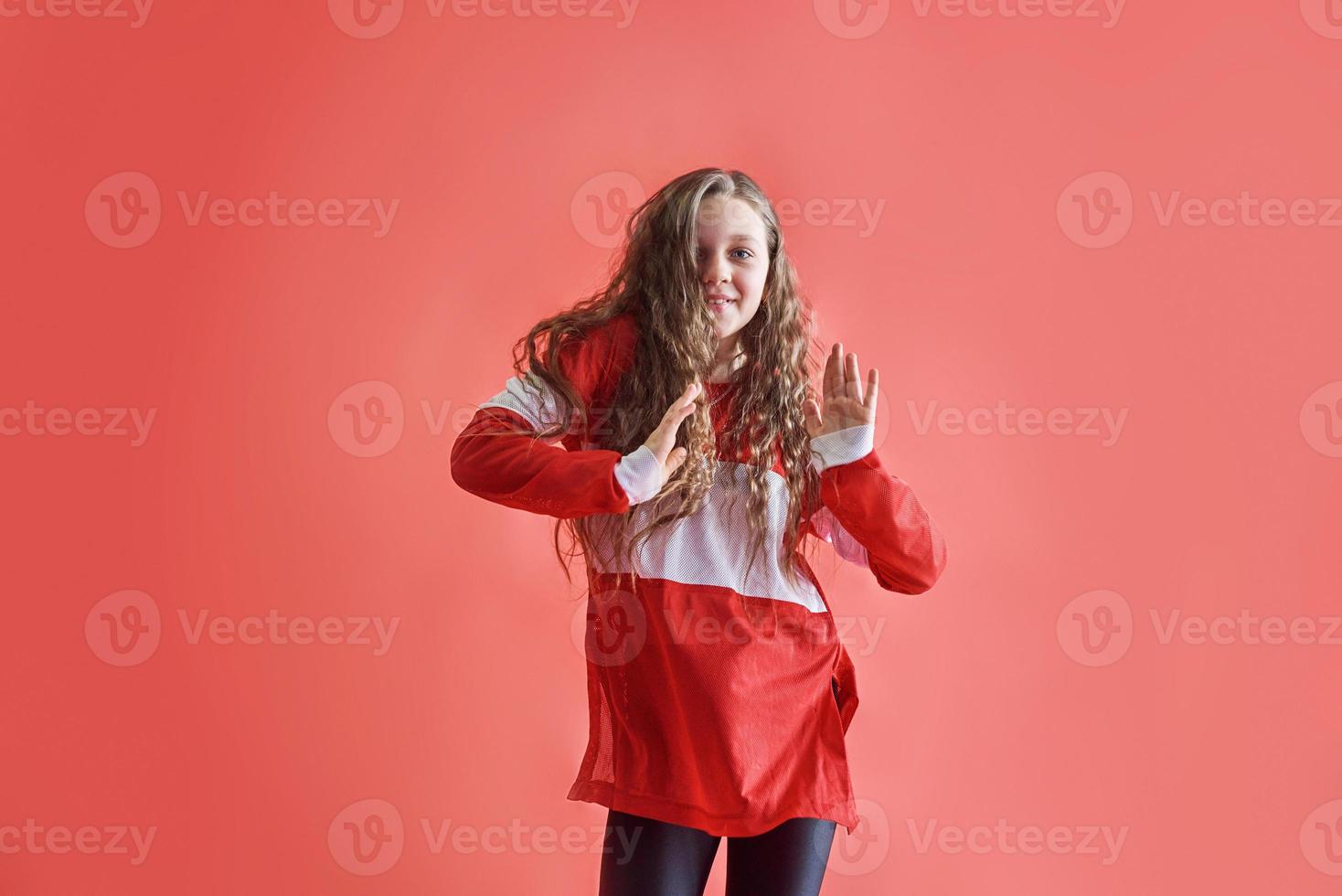 Young beautiful cute girl dancing on red background, modern slim hip-hop style teenage girl jumping photo