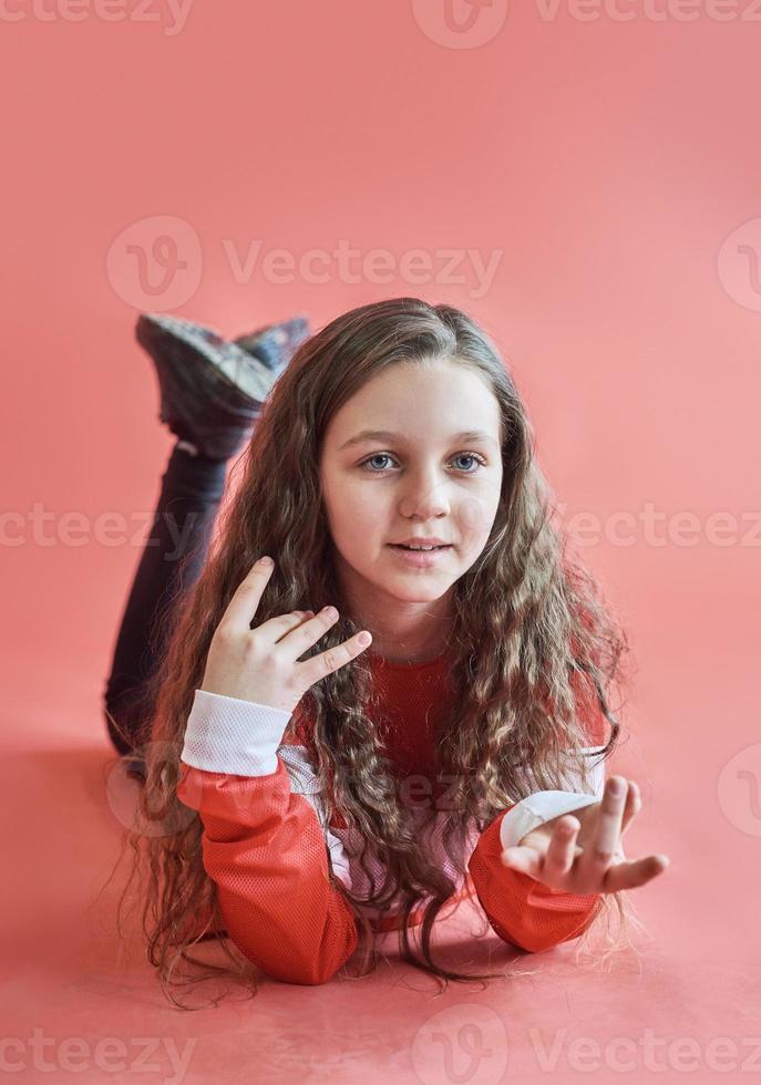 Young urban woman dancing on red background, modern slim hip-hop style teenage girl photo