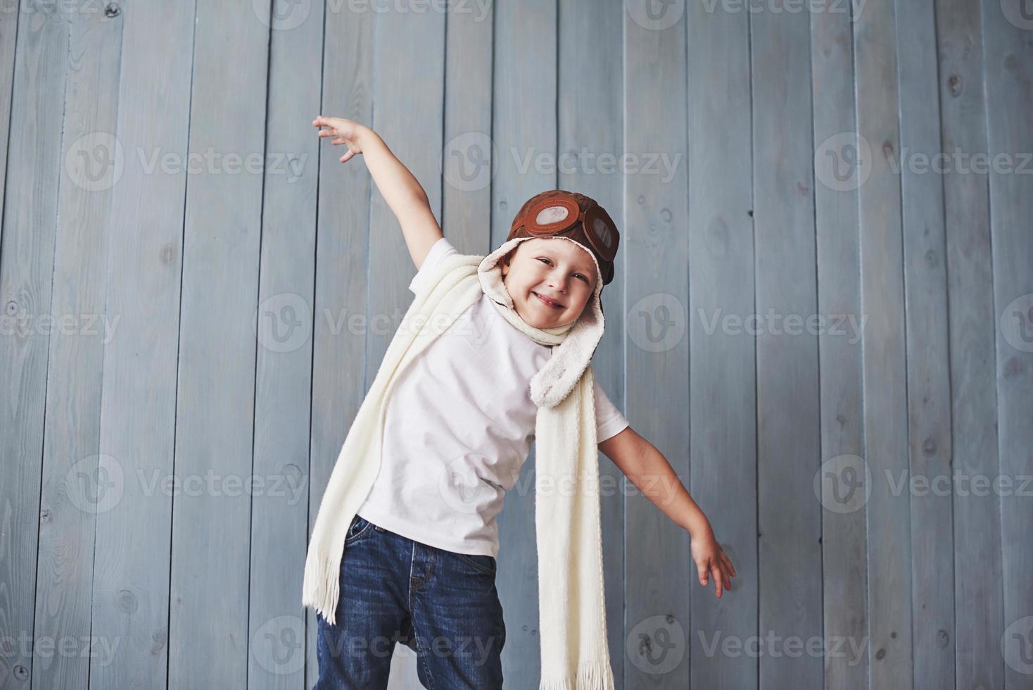 hermoso niño sonriente en casco sobre un fondo azul jugando con un avión. concepto piloto vintage foto