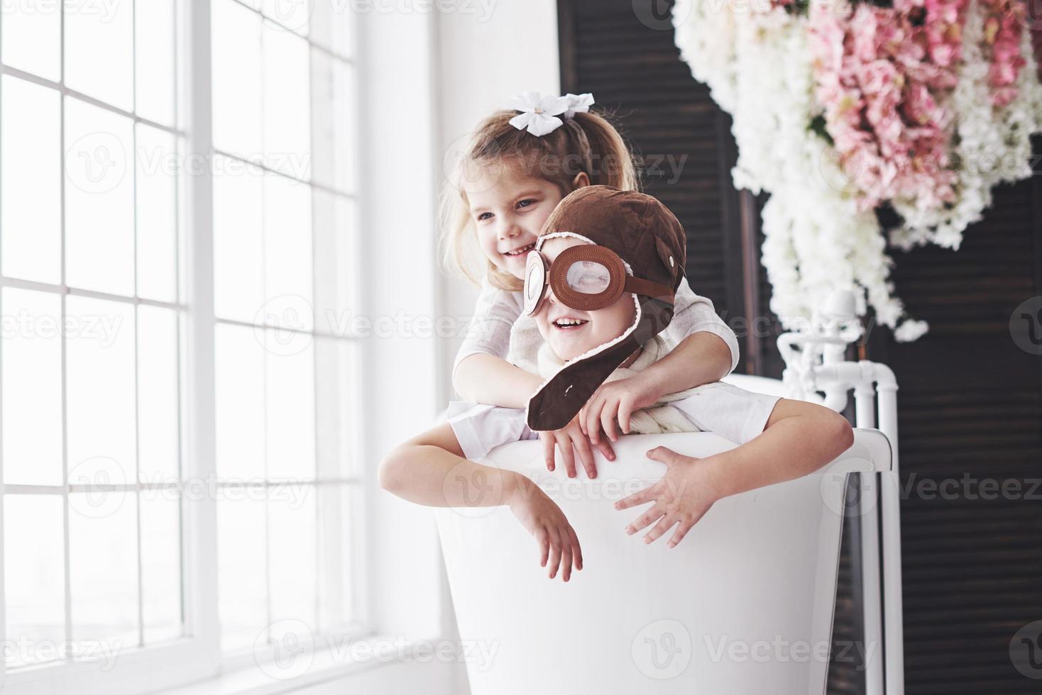 retrato de una niña y un niño con sombrero de piloto jugando en el baño a los pilotos o marineros. el concepto de viaje, infancia y realización de sueños foto