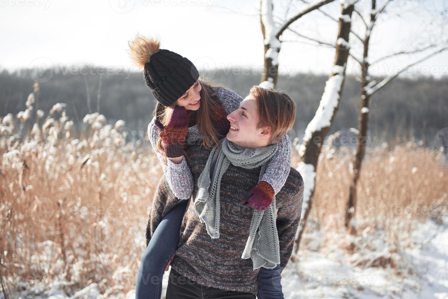 Happy young couple has fun on fresh snow at beautiful winter sunny day on vacation photo