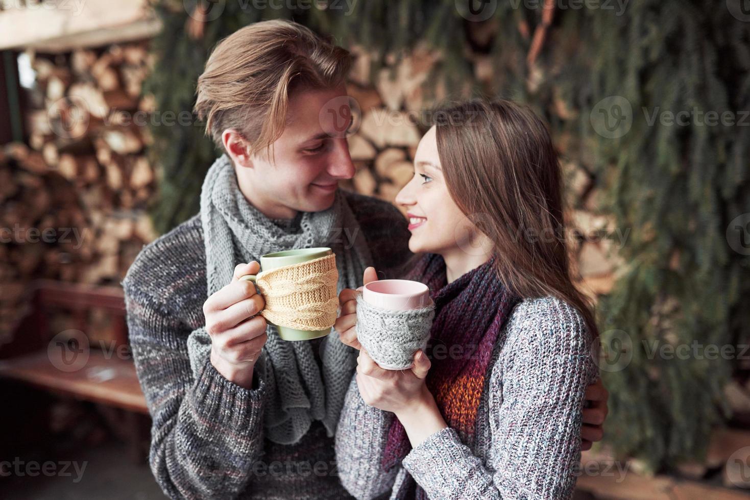 pareja joven desayunando en una cabaña romántica al aire libre en invierno. vacaciones de invierno y vacaciones. Pareja de Navidad de hombre y mujer felices beben vino caliente. pareja enamorada foto