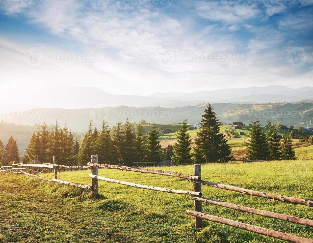 Beautiful summer mountain landscape at sunshine. View of the meadow fenced fence. Rural landscape photo