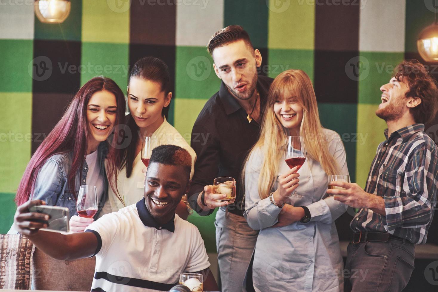 Self portrait of mixed race unity of african, american, asian, caucasian friends, happy bearded men and beautiful women in red santa hat showing thumb up, like, ok gesture to the camera in office photo