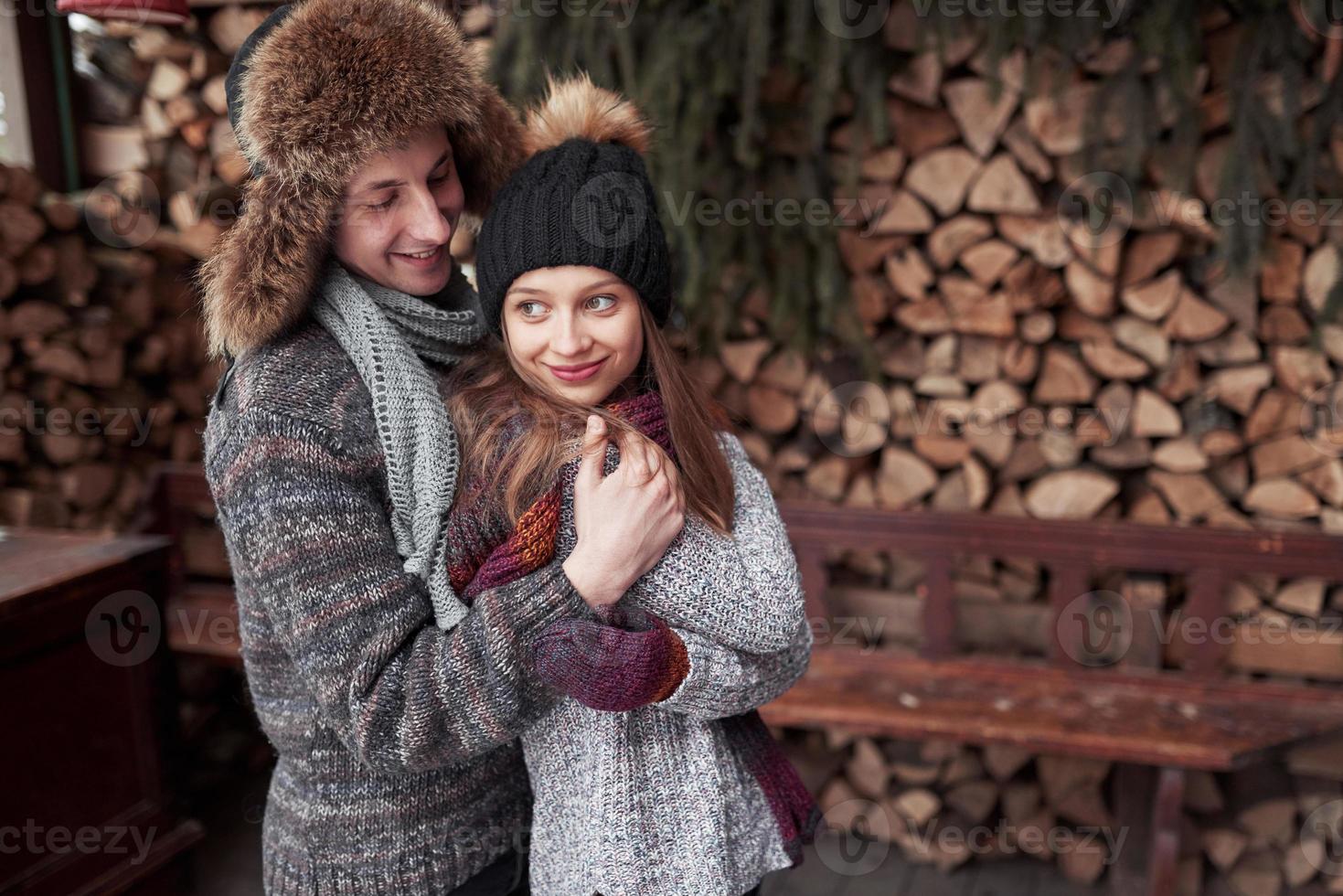Pareja joven alegre en una cabaña en un romántico paisaje en invierno foto