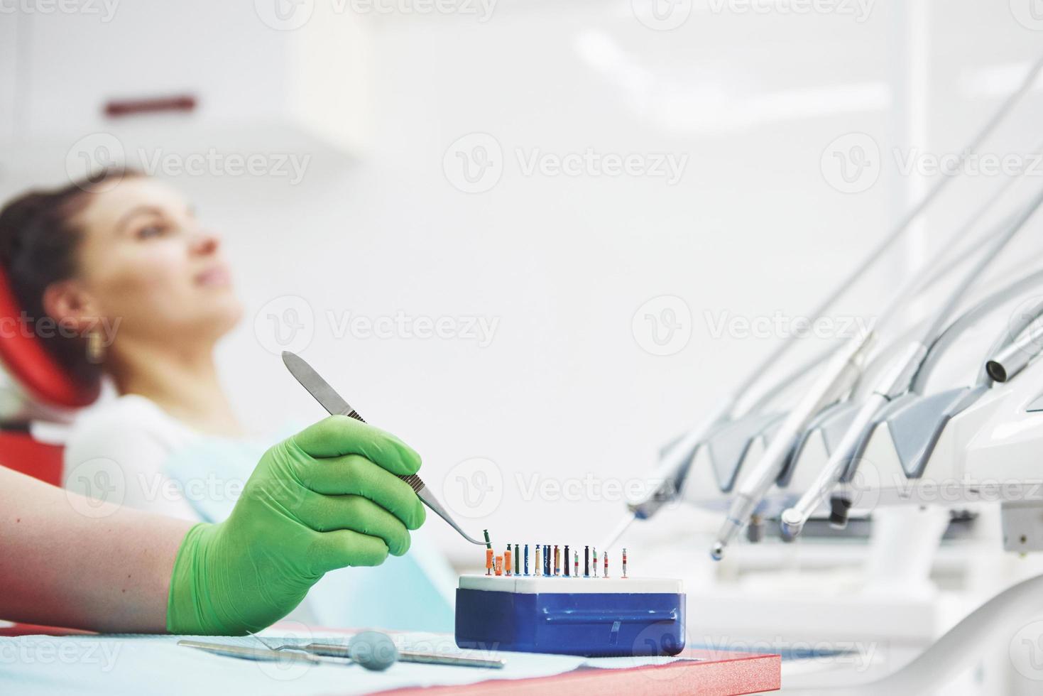 un paciente en una clínica dental se sienta en una silla y el médico prepara las herramientas para el tratamiento foto