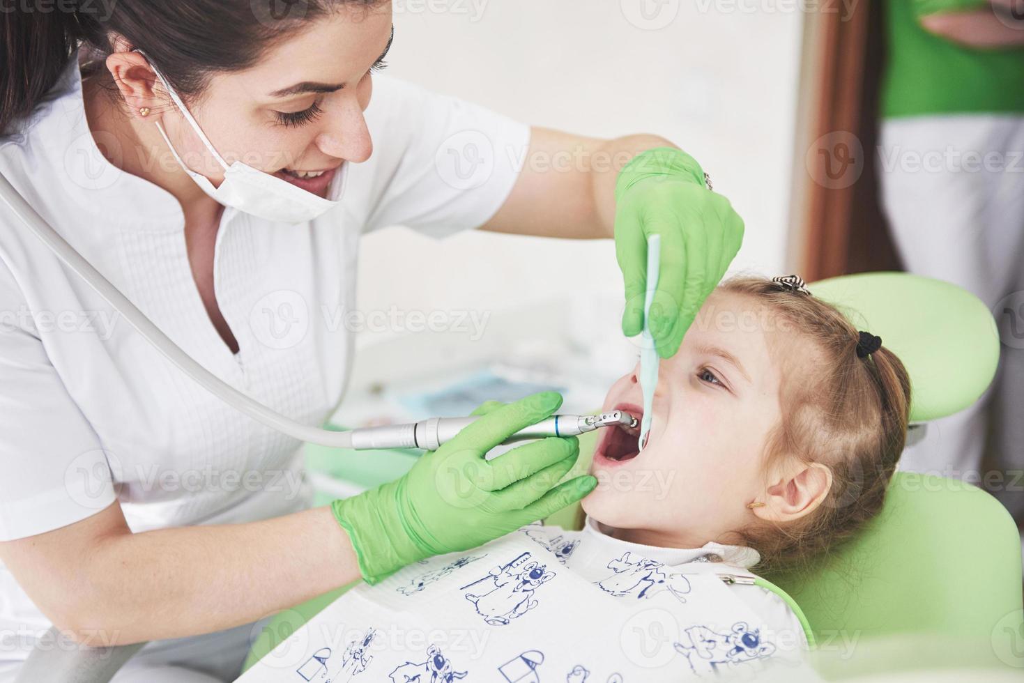 chequeo de dientes en el consultorio del dentista. Dentista examinando los dientes de las niñas en la silla del dentista foto