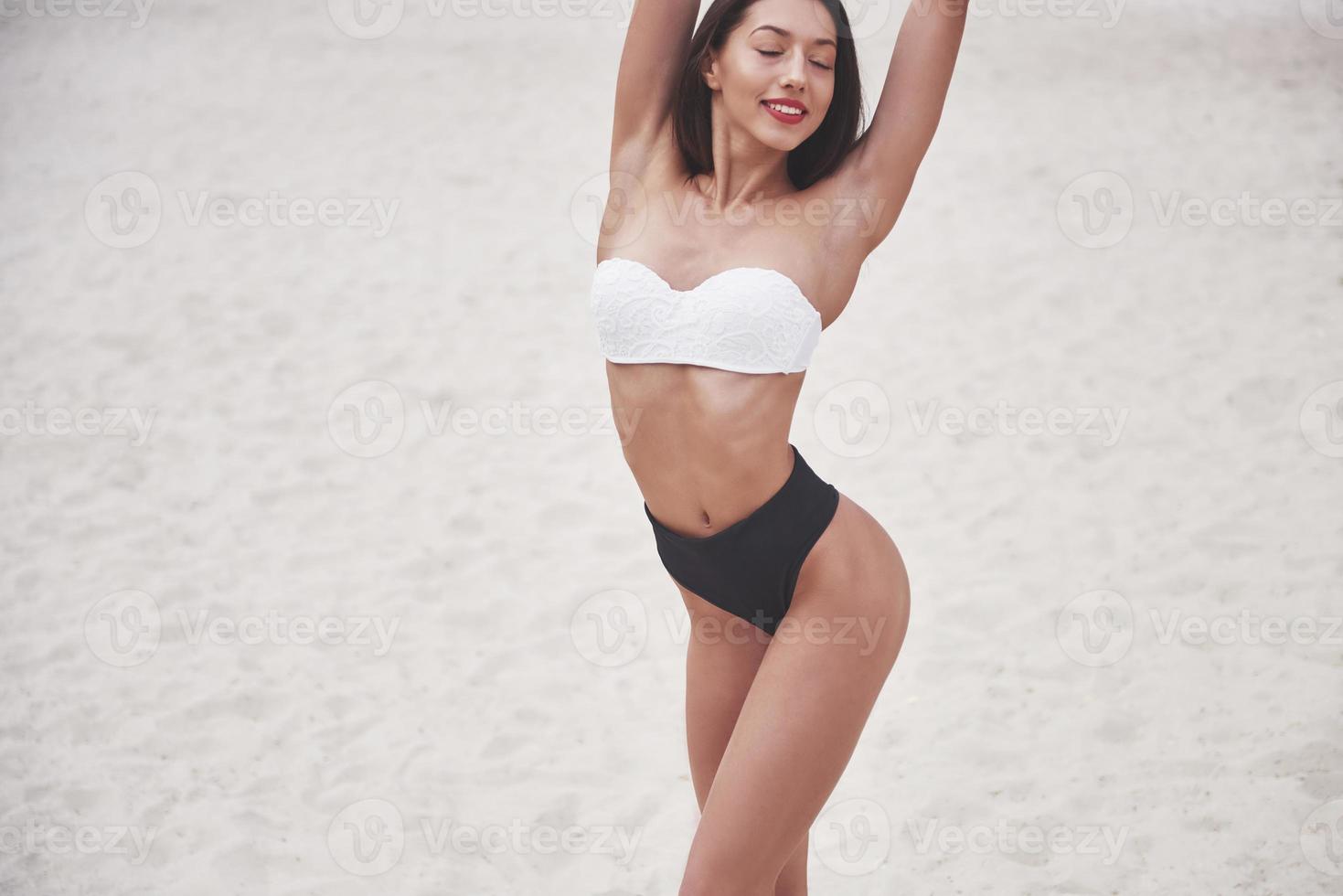 Beautiful slim luxury girl in bikini on the sand beach on a tropical island. Sexy tanned body and perfect figure photo