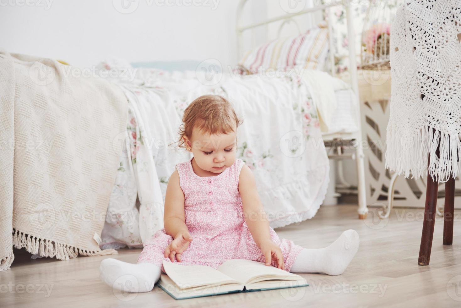 Beautiful little girl read book with her favorite bear on a soft plush blanket photo