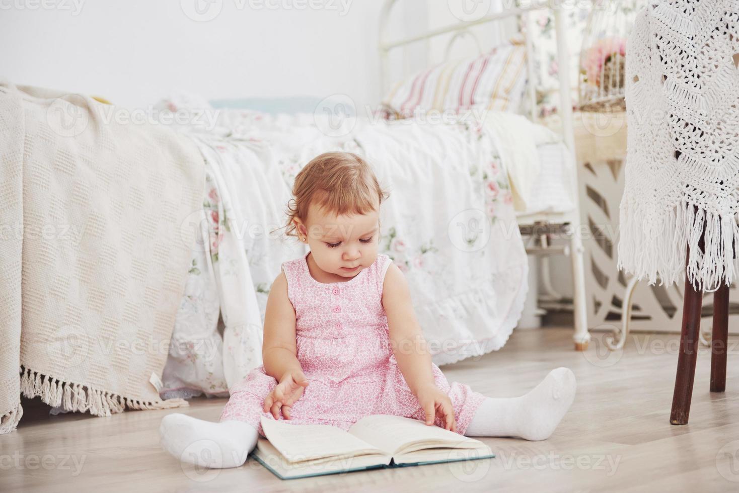 hermosa niña leyendo un libro con su oso favorito en una manta de felpa suave foto