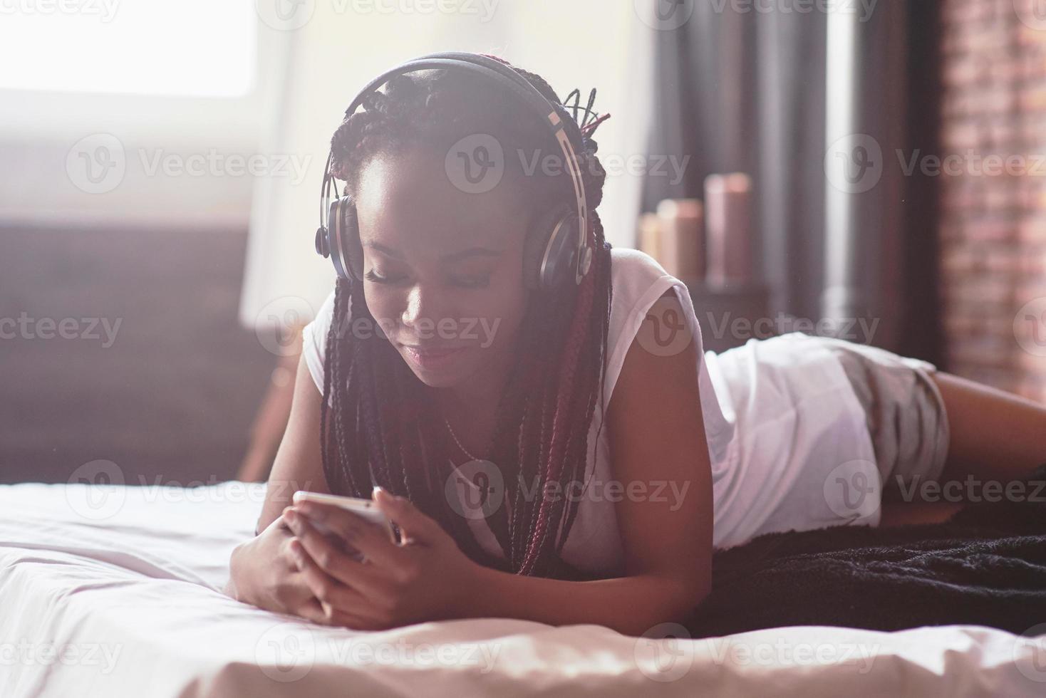 Portrait of beautiful woman waking up in her bed and looks into the phone. Check social networks, send sms. The girl is wearing a T-shirt photo