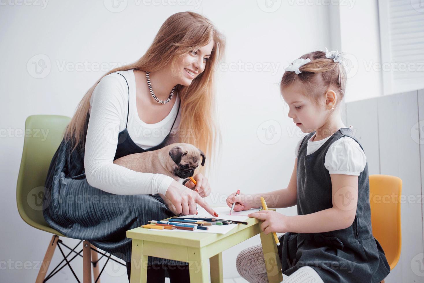 mother and child daughter draws are engaged in creativity in kindergarten. small pug with them photo