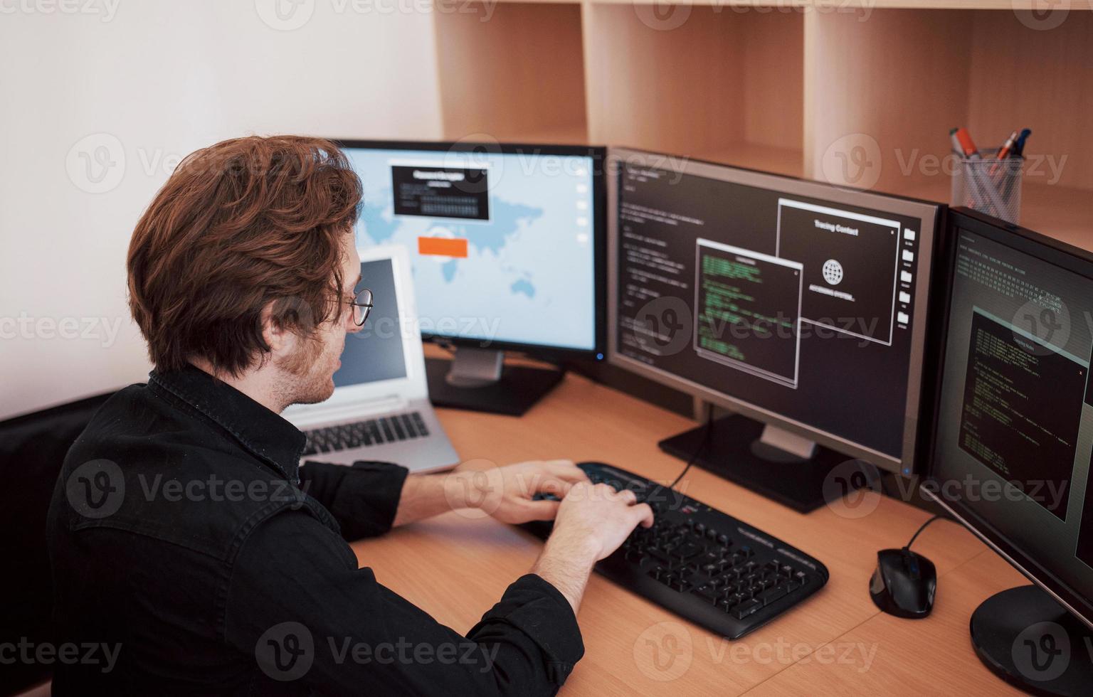 Male programmer working on desktop computer with many monitors at office in software develop company. Website design programming and coding technologies photo