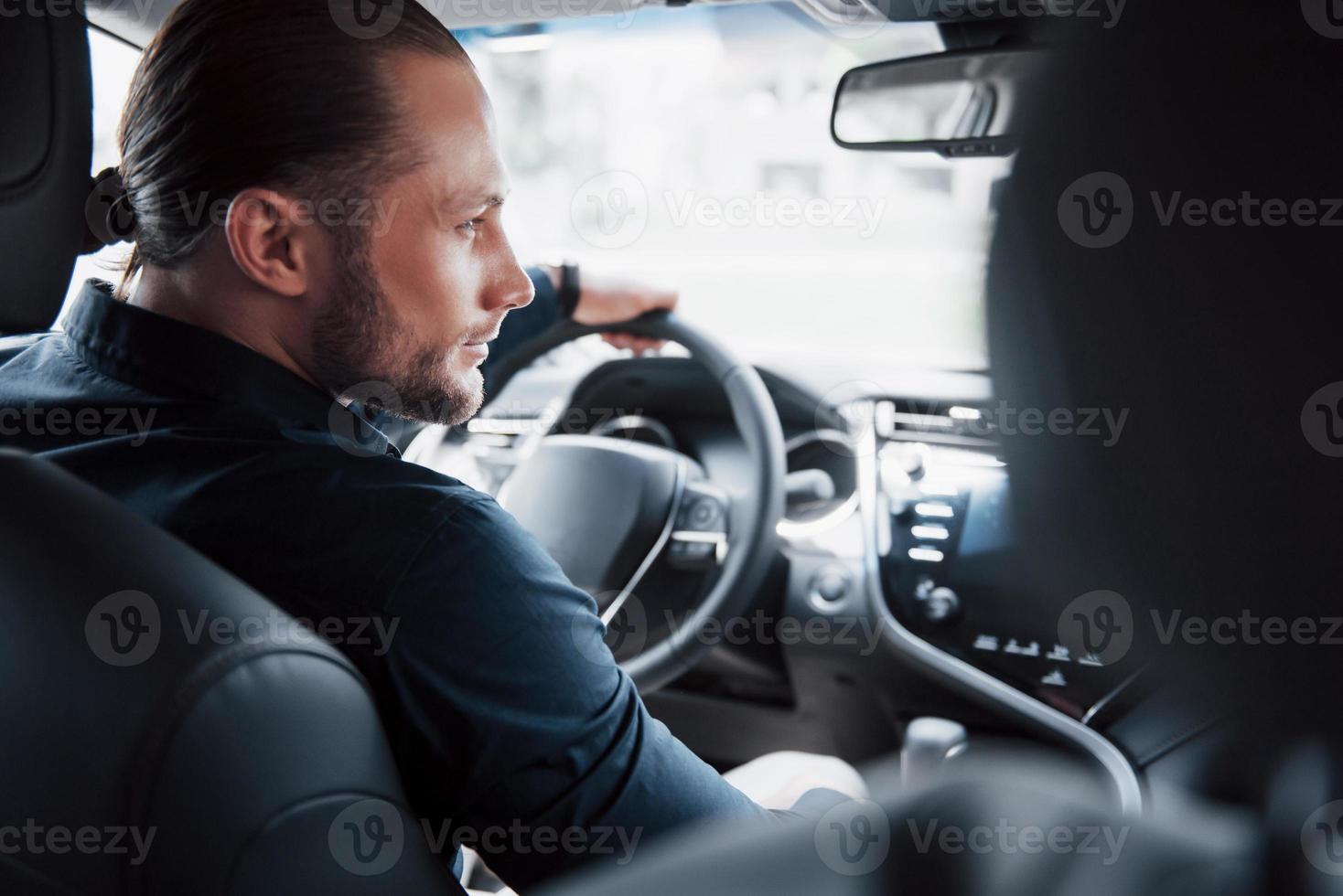 Confiado joven empresario sentado al volante de su coche nuevo foto