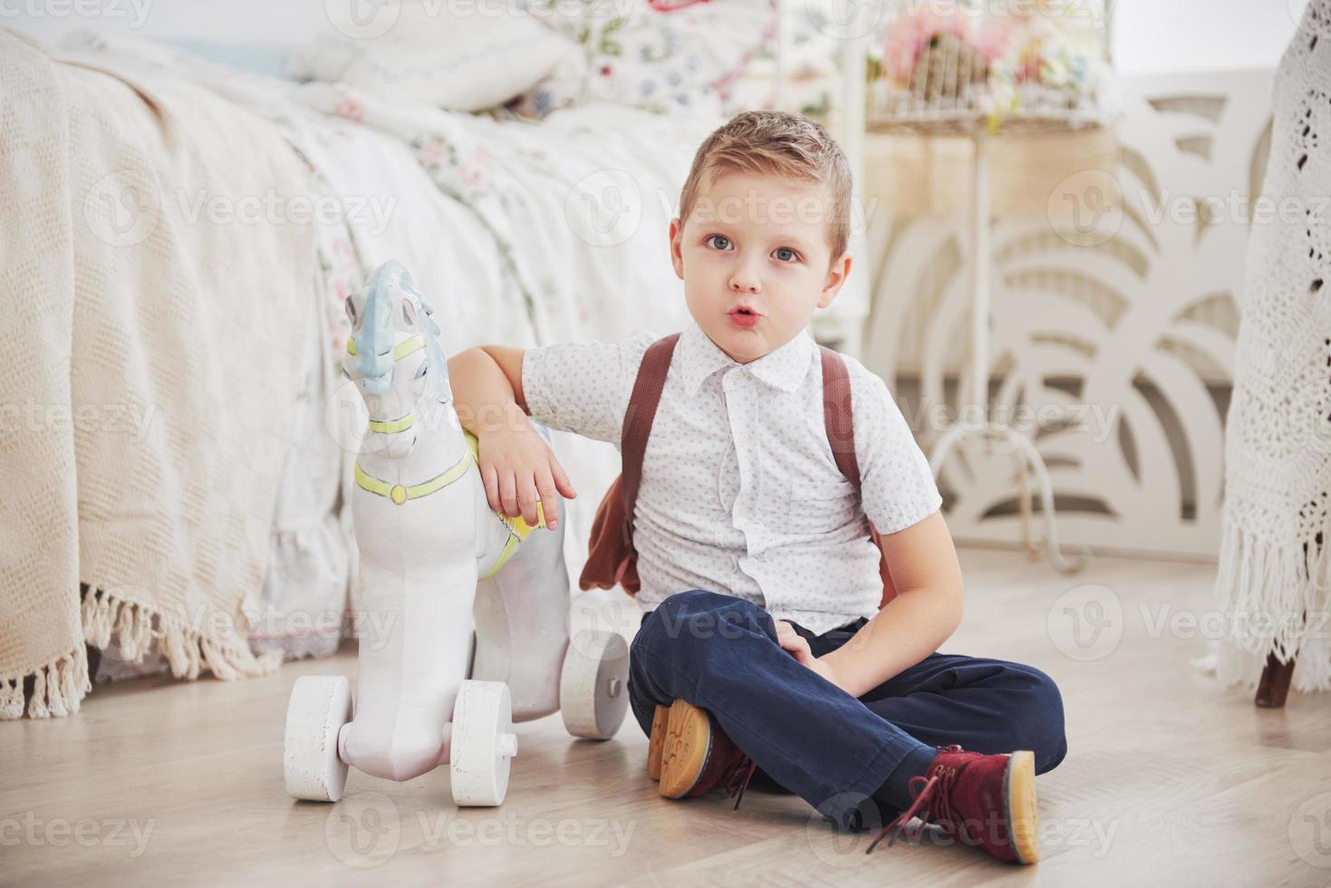 niño lindo va a la escuela por primera vez. niño con mochila y libro. niño hace un maletín, habitación infantil sobre un fondo. De vuelta a la escuela foto