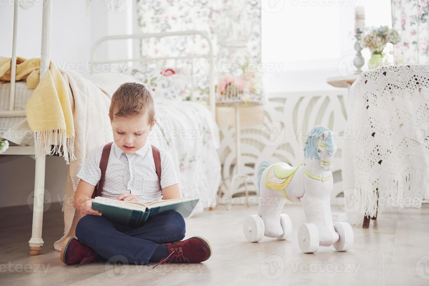 niño lindo va a la escuela por primera vez. niño con mochila y libro. niño hace un maletín, habitación infantil sobre un fondo. De vuelta a la escuela foto