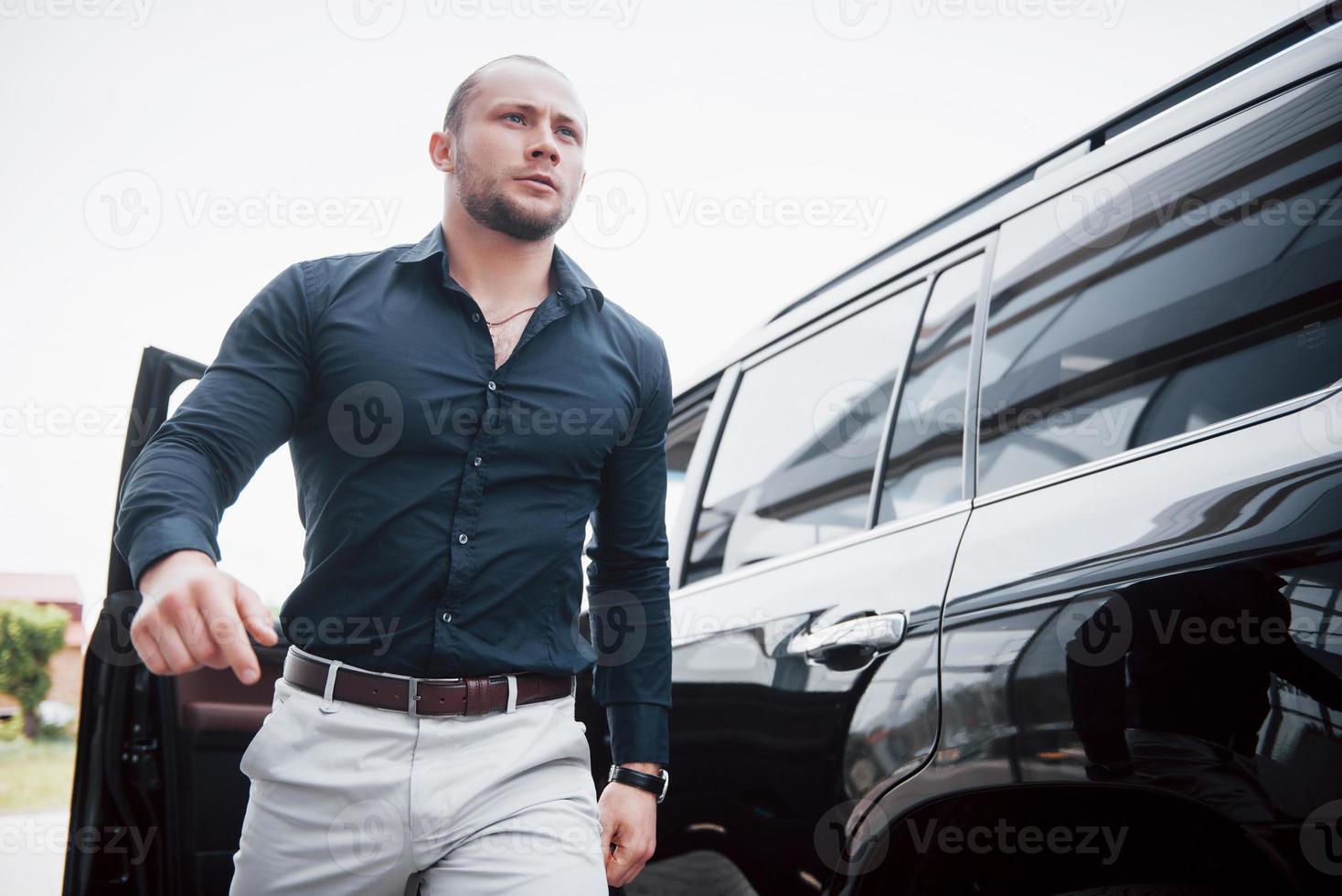 un joven y sólido hombre de negocios y su auto cerca de la oficina. foto