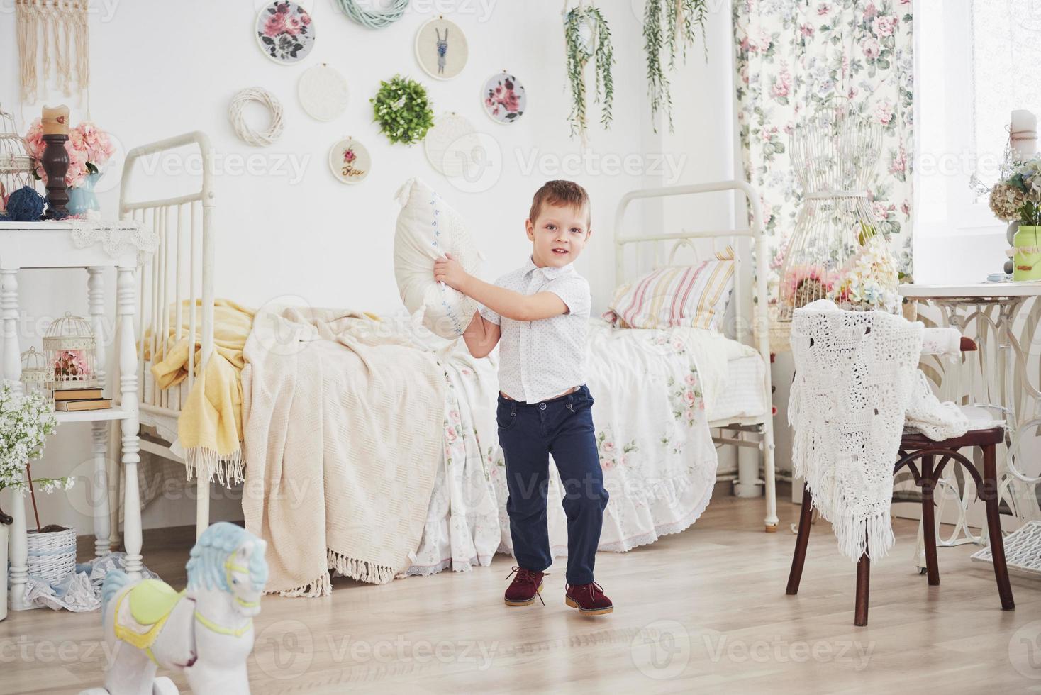 niño con camisa blanca con almohada. pelea de almohadas foto