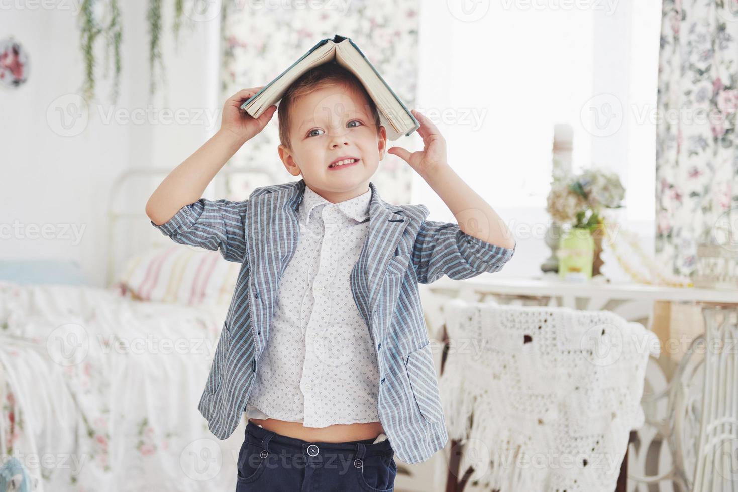 foto de colegial diligente con el libro en la cabeza haciendo los deberes. el colegial está cansado de hacer los deberes