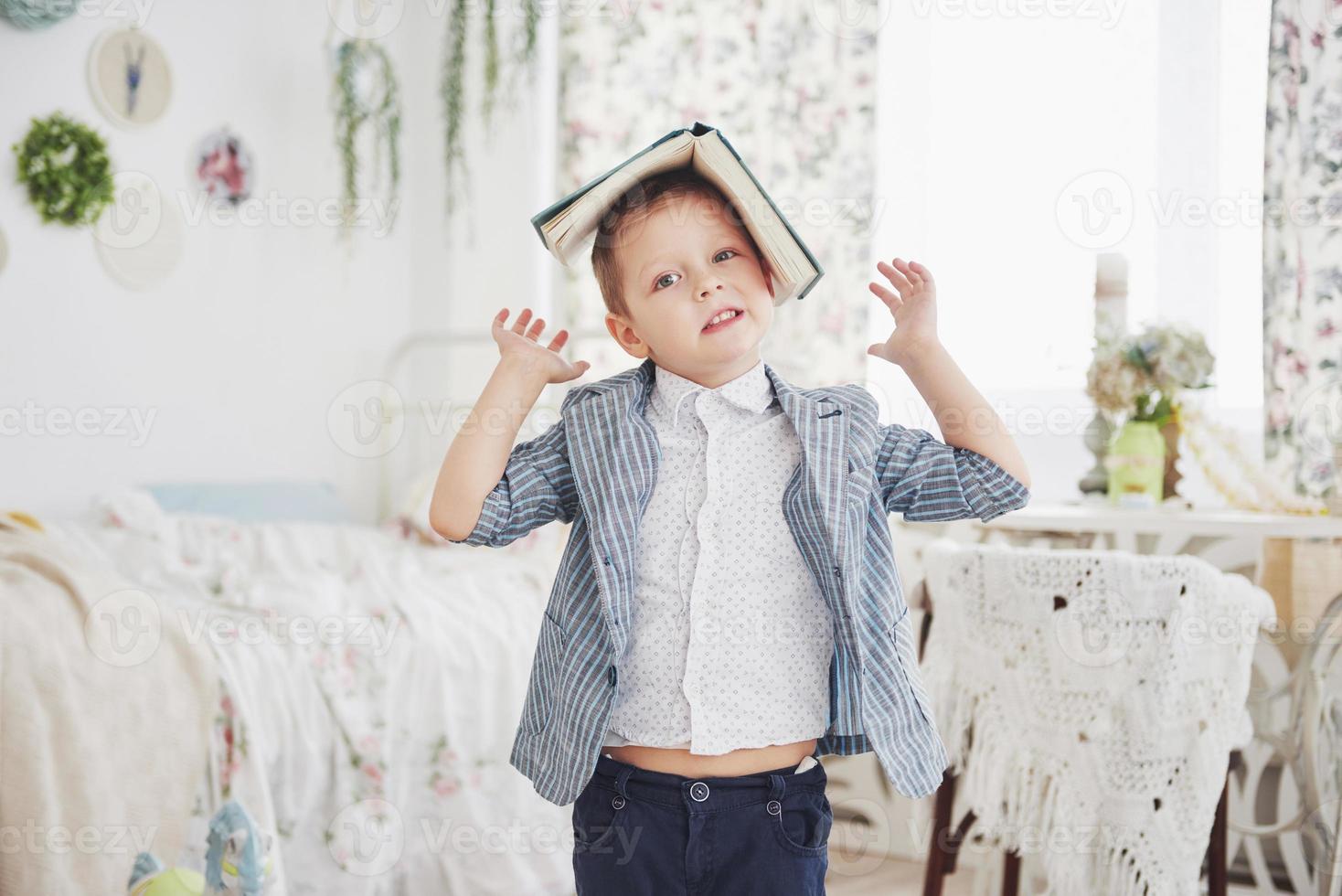 Foto de colegial diligente con un libro en la cabeza que no quiere estudiar e ir a la escuela. el colegial está cansado de hacer los deberes