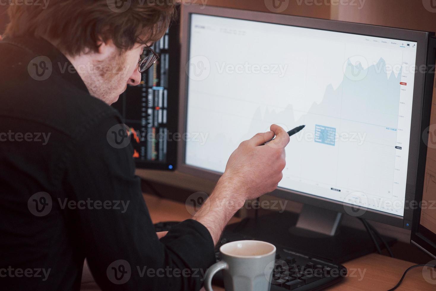 analizar datos. Close-up de joven empresario apuntando a los datos presentados en el gráfico con lápiz mientras trabajaba en la oficina creativa foto