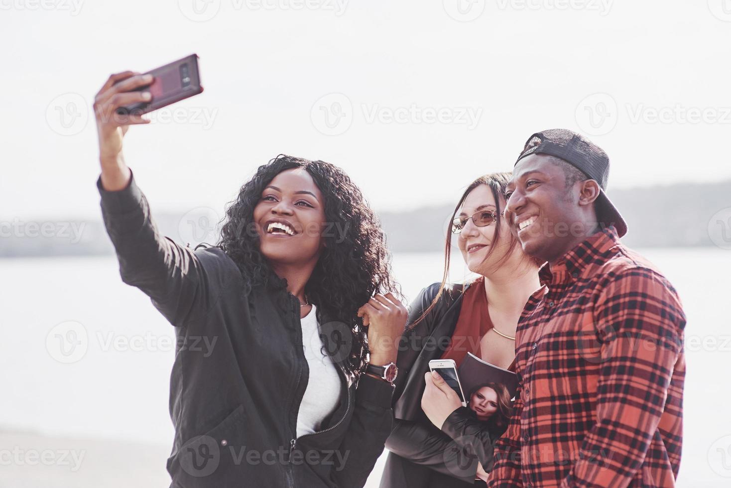 A group of young people make a sephi in a park on the shore of a lake on a sunny day photo