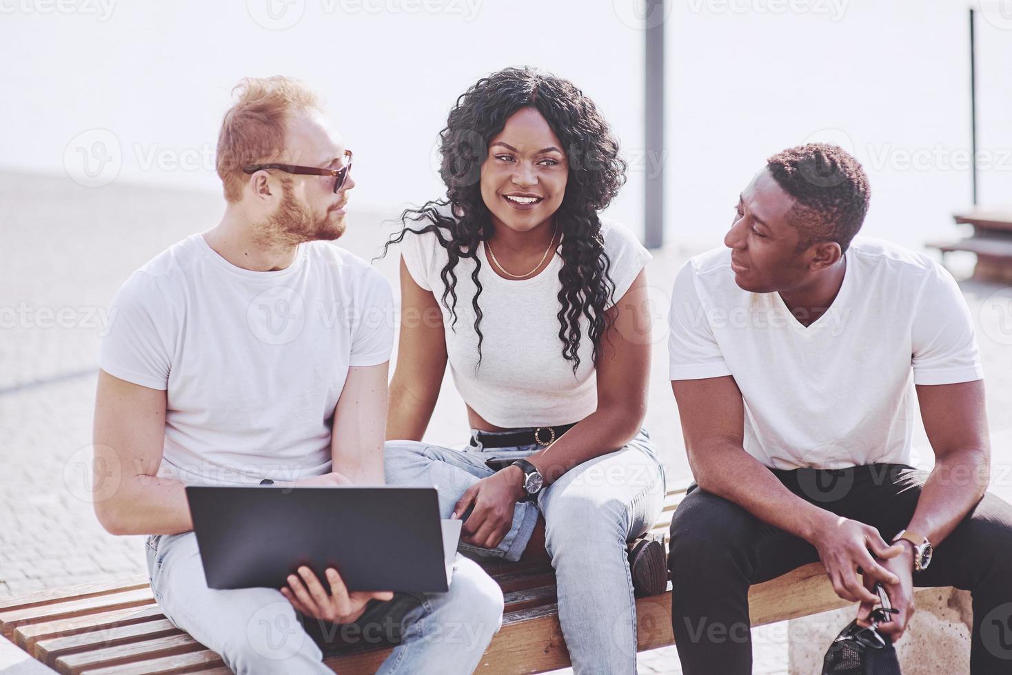 Beautiful multi ethnic friends using a laptop in the Street. Youth lifestyle concept photo