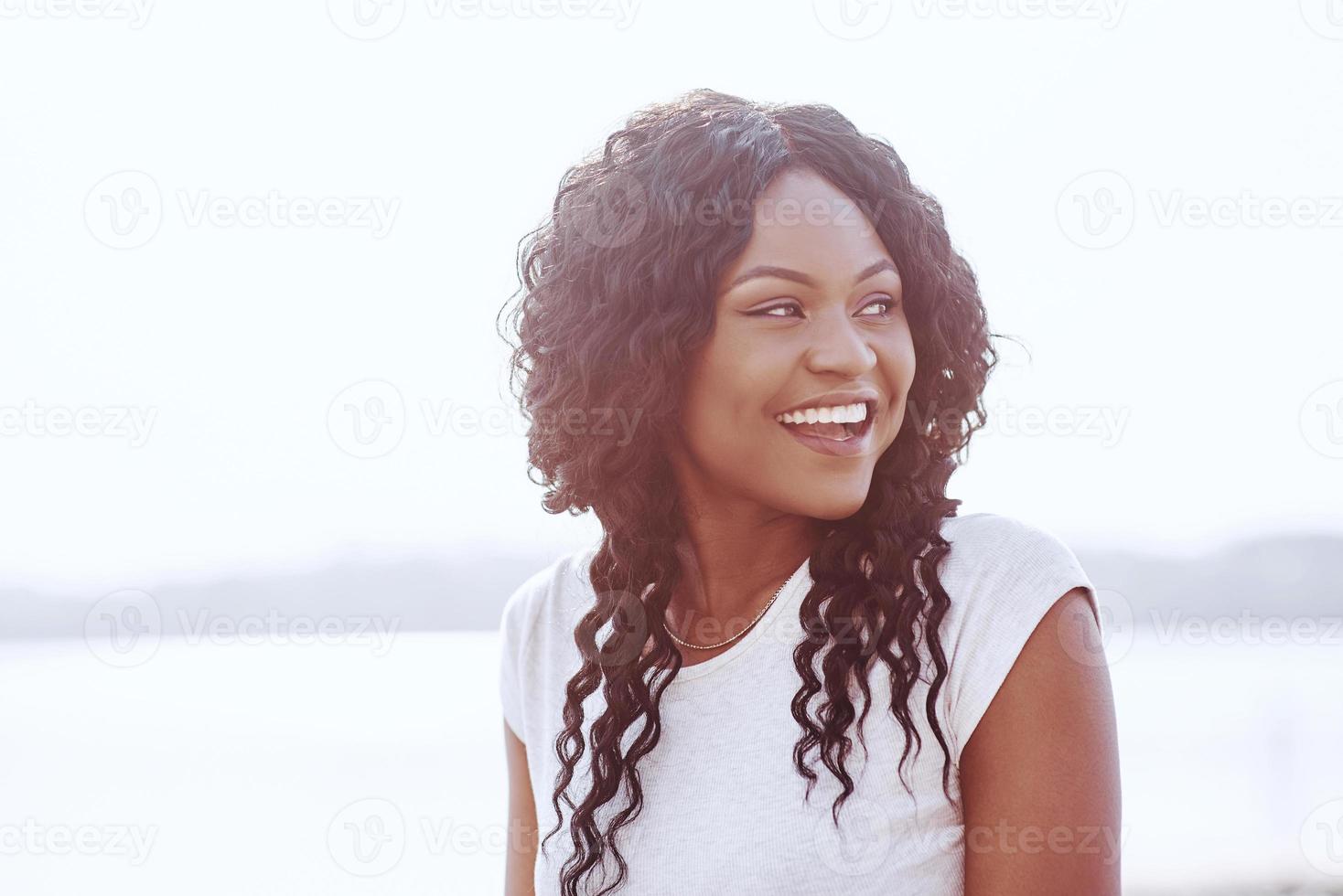 retrato, de, sonriente, joven, mujer negra, con, luz del sol, destello foto