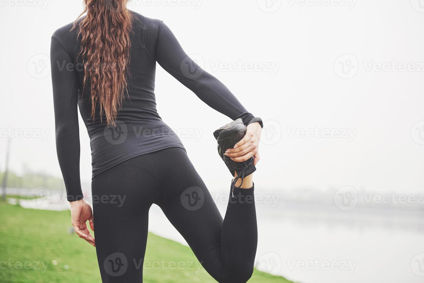 Joven corredor mujer fitness estirando las piernas antes de ejecutar en el parque foto