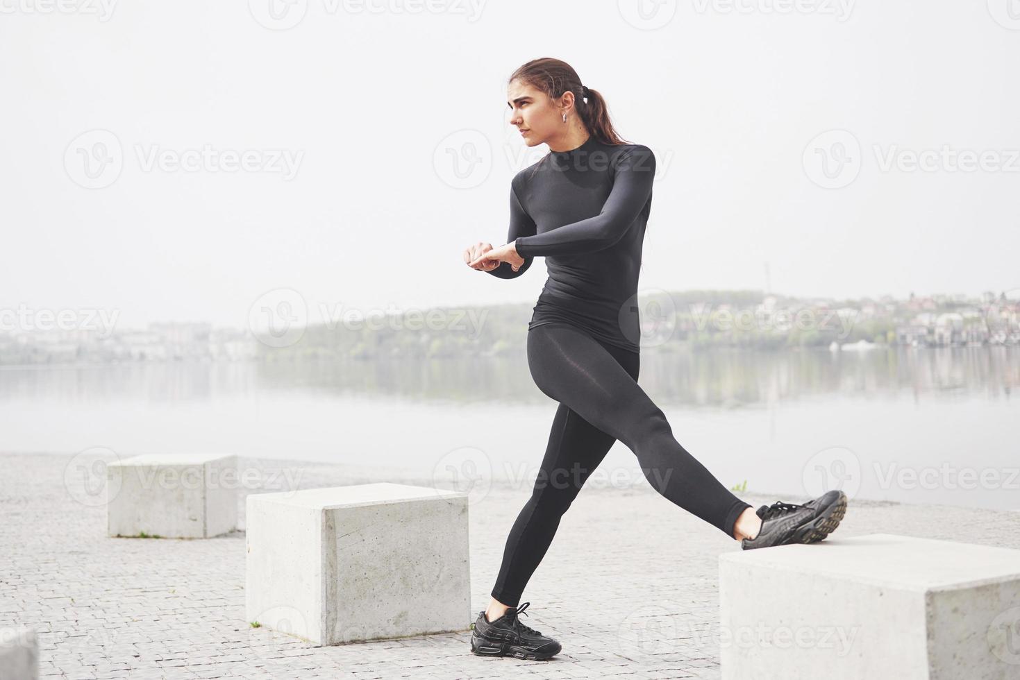 A young woman is engaged in sports on the shore of a lake in the park photo