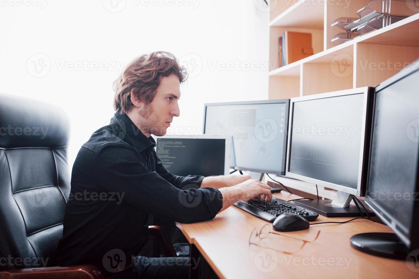 Male programmer working on desktop computer with many monitors at office in software develop company. Website design programming and coding technologies photo