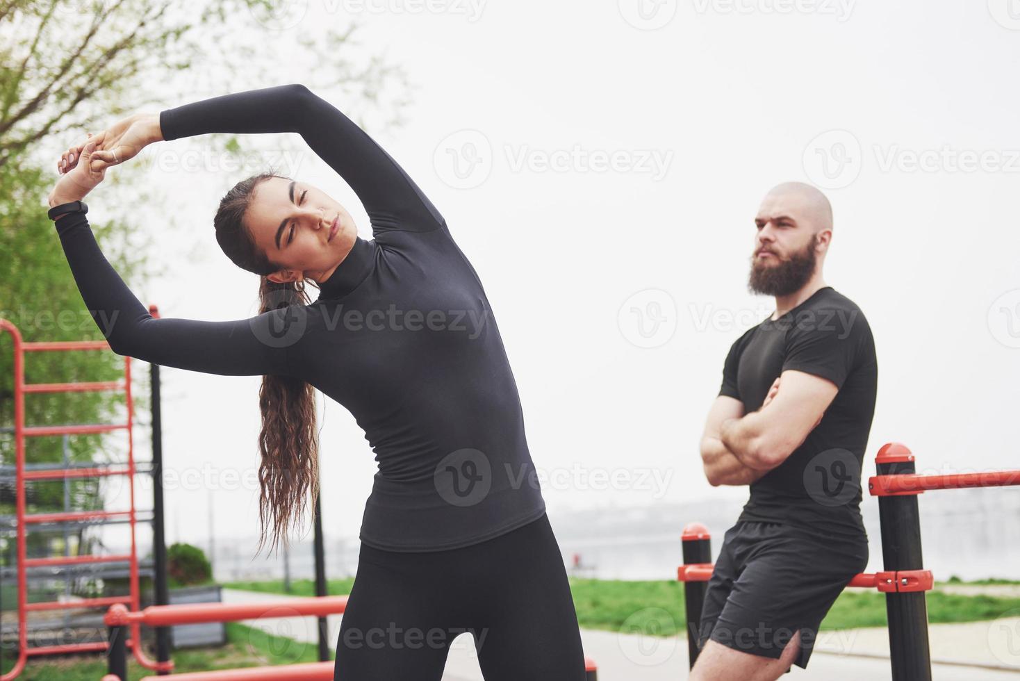 Young man and woman perform exercises and stretch marks before doing sports photo