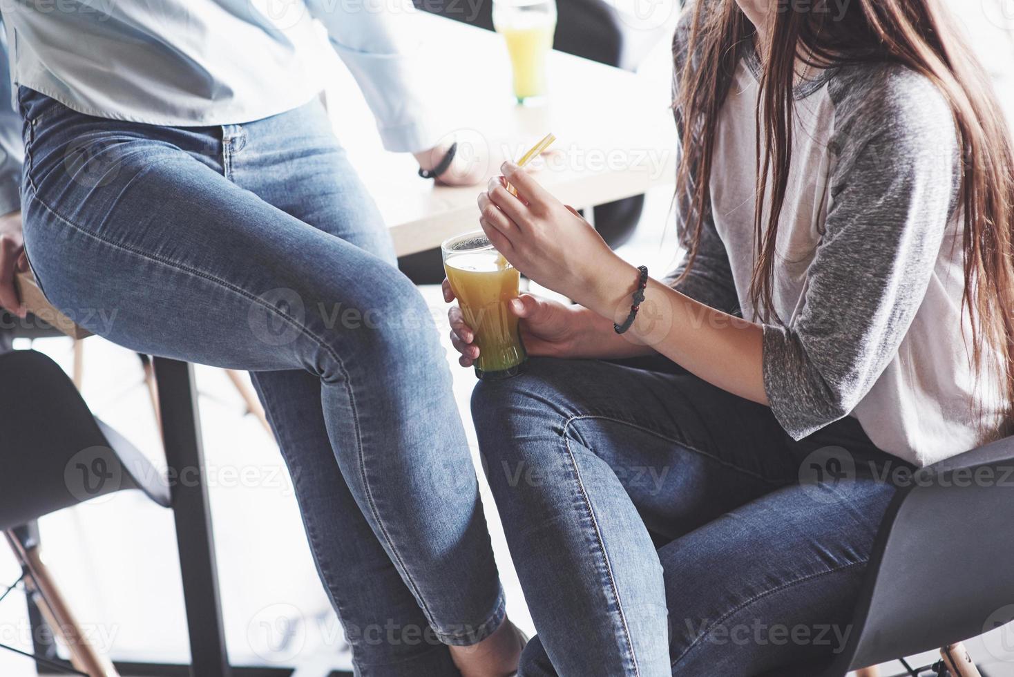 Two beautiful twin girls spend time drinking juice. Sisters relaxing in a cafe and having fun together photo