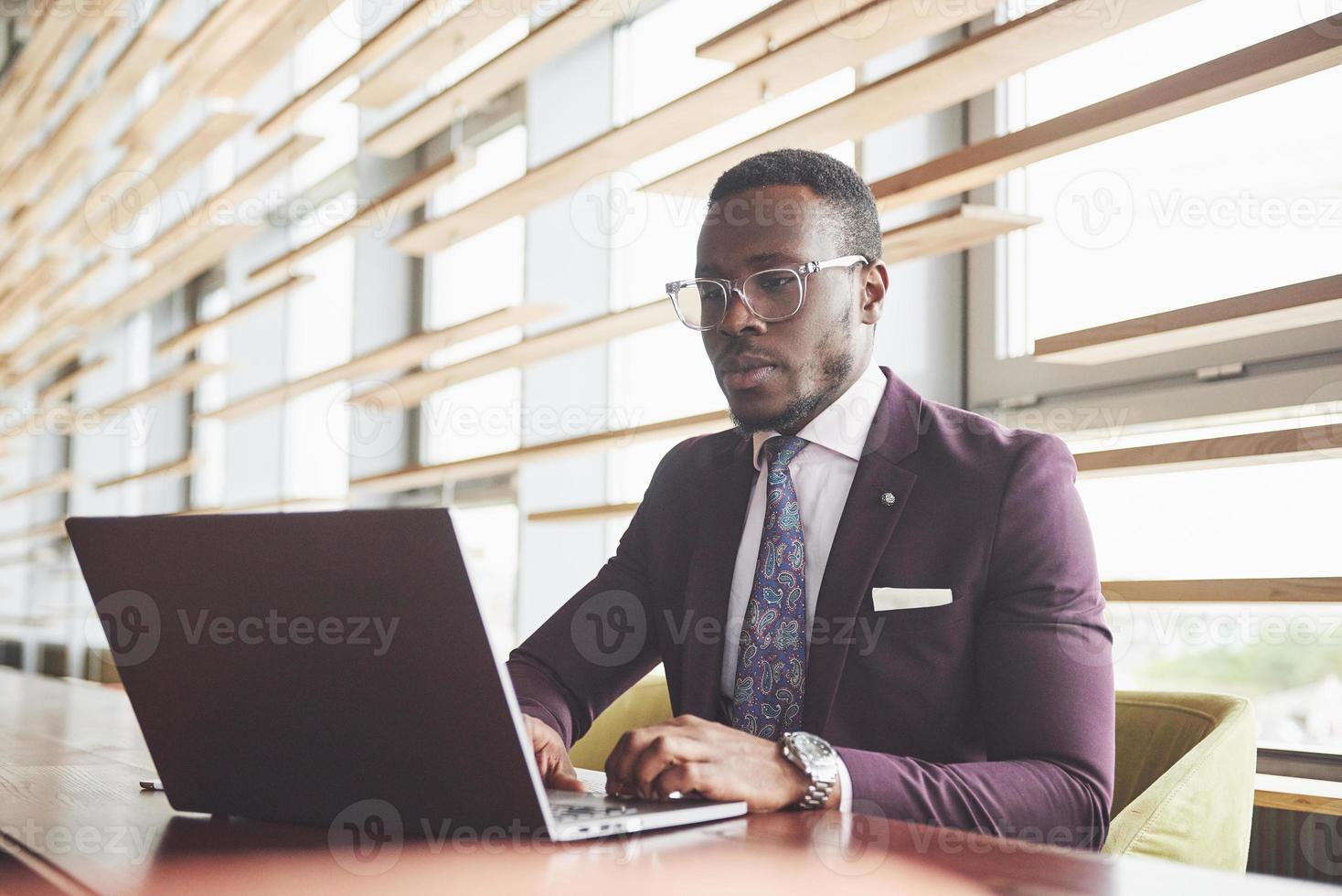 Una hermosa y elegante empresaria afroamericana vistiendo un traje usa su computadora portátil mientras trabaja foto