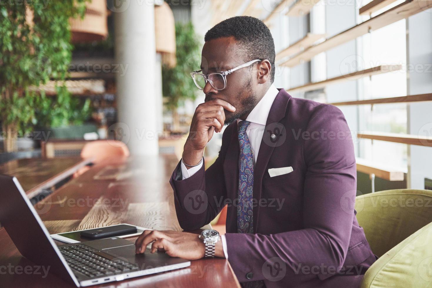 A beautiful stylish African American businesswoman wearing a suit uses his laptop while working photo