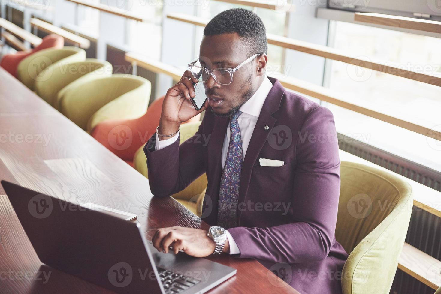 Una hermosa y elegante empresaria afroamericana vistiendo un traje usa su computadora portátil mientras trabaja foto