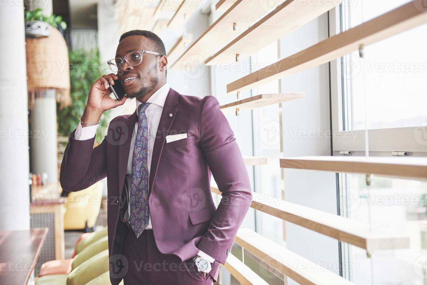 Retrato de un joven y guapo empresario afroamericano hablando en un traje por teléfono foto