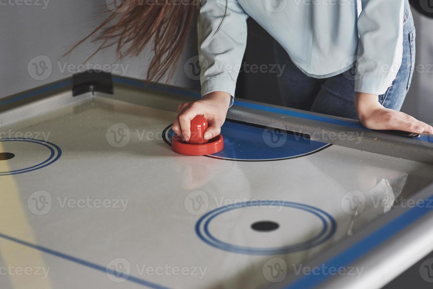 Manos de jóvenes sosteniendo el delantero en la mesa de hockey de aire en la sala de juegos foto