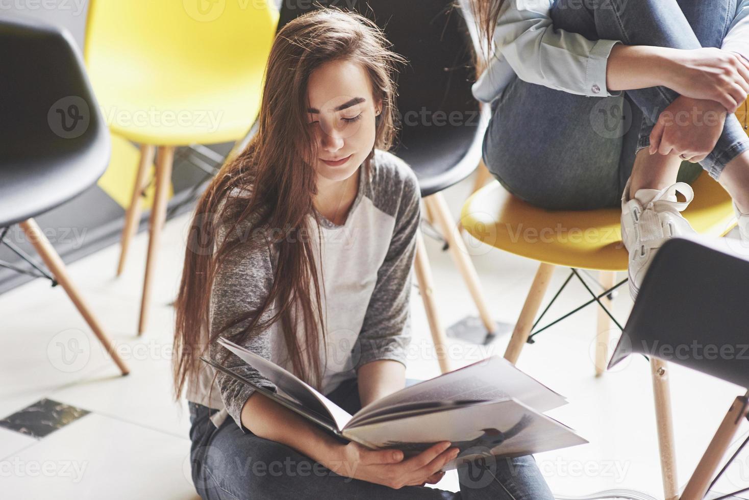 dos hermosas niñas gemelas pasan tiempo leyendo un libro en la biblioteca por la mañana. hermanas relajándose en un café y divirtiéndose juntas foto