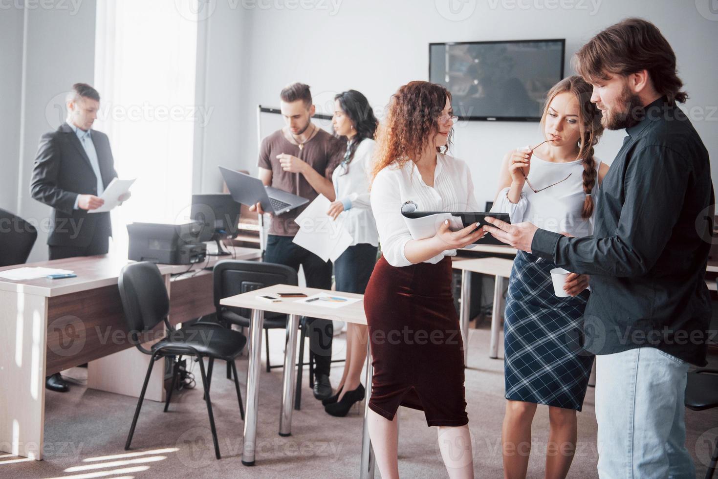 A group of young colleagues talks about working issues in modern office space. photo