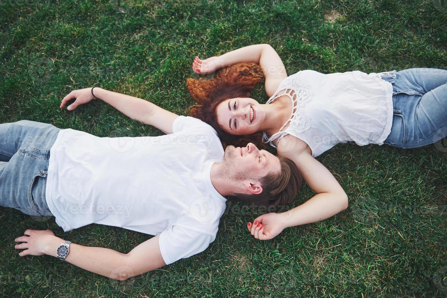 Romantic couple of young people lying on grass in park. They look happy. View from above. photo